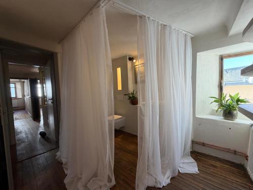 a white curtain in a room with a window at Our Hippie Castle Vianden - Unique Bohemian Guesthouse in Vianden