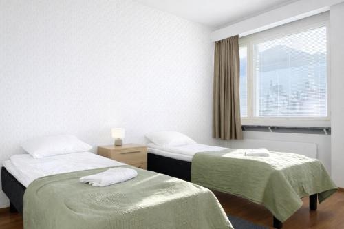 two beds in a room with a window at Helmi Pori Centrum in Pori