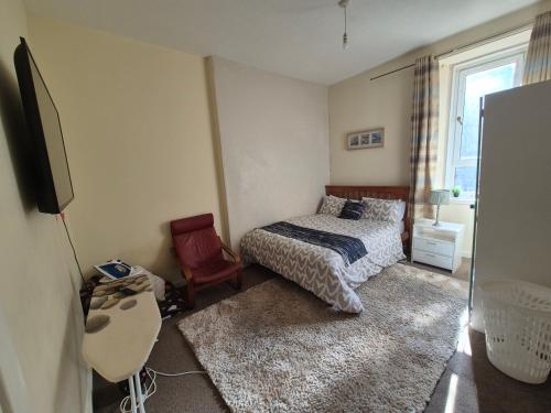 a bedroom with a bed and a tv and a chair at Cosy and Bright 3-bedroom flat in Glasgow