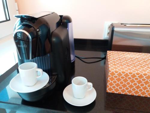 a coffee maker and two cups on a counter at Quad Avenue in Lisbon