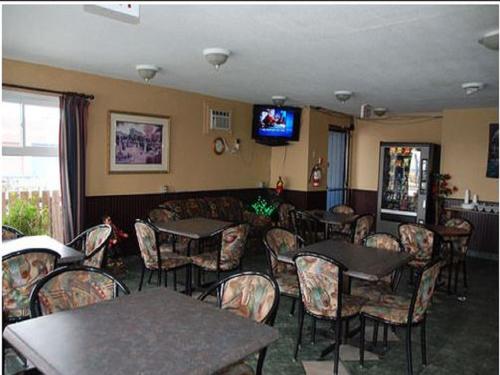 a restaurant with tables and chairs and a flat screen tv at Best Lodge Motel in Lloydminster