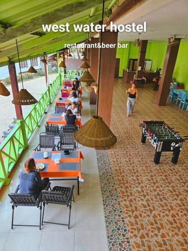 a group of people sitting at tables in a restaurant at west water hostel in Ban Khouaphan