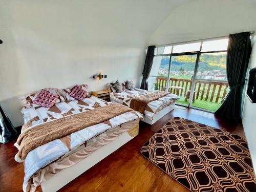 two beds in a room with a large window at Glamping Calla in Banjarnegara