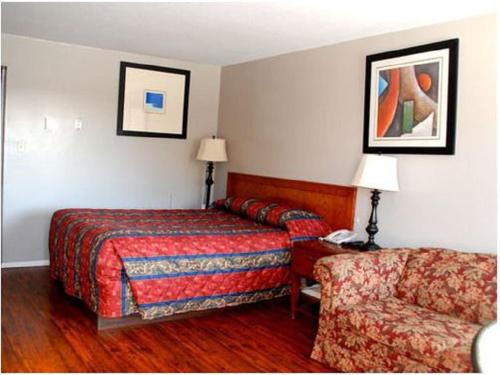 um quarto de hotel com uma cama e uma cadeira em Best Lodge Motel em Lloydminster