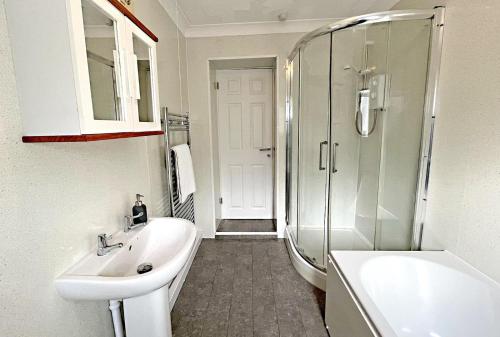 a white bathroom with a sink and a shower at Pleasant View Cottage in Trehafod