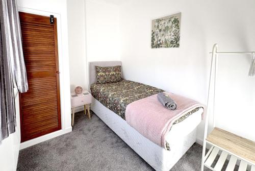 a small bedroom with a bed with a pink blanket at Pleasant View Cottage in Trehafod