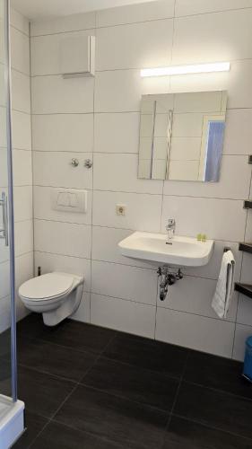 a white bathroom with a sink and a toilet at Gästehaus König in Weinstadt
