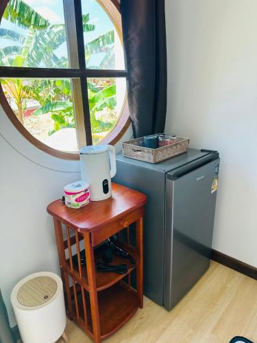a small table next to a refrigerator and a window at Lanta Junli House in Ko Kam Yai