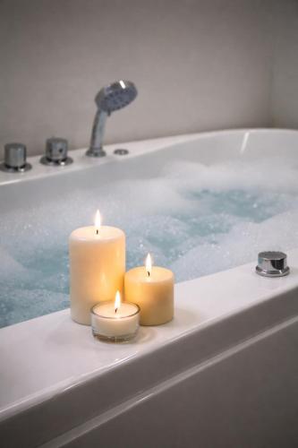 two candles sitting in a bath tub with a bath tub at Luksusowy Apartament W Centrum Gdańska in Gdańsk