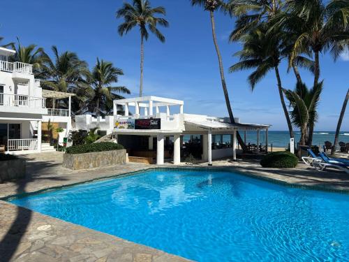a swimming pool in front of a house and the ocean at Panoramic Views Two Decks 1st Row Ocean Kite Beach in Cabarete