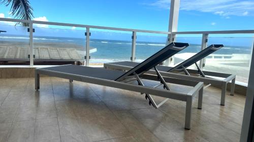two chairs sitting on a balcony overlooking the beach at Panoramic Views Two Decks 1st Row Ocean Kite Beach in Cabarete