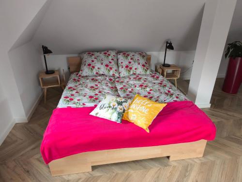 a bed with a red blanket and pillows on it at Bukowy Zakątek in Brenna