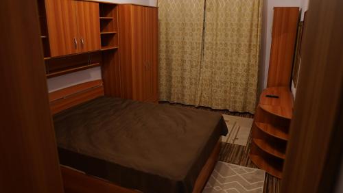 a small bedroom with a bed and wooden cabinets at Apartament 2 camere SIBIU-SELIMBAR in Şelimbăr