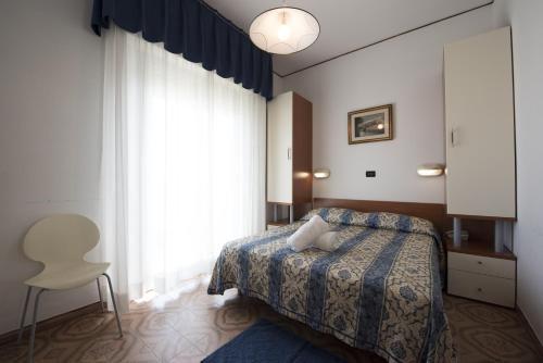 a bedroom with a bed and a chair and a window at Hotel Gigliola in Bellaria-Igea Marina