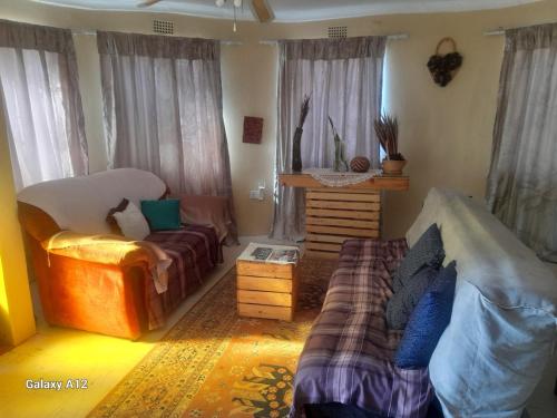 a living room with a couch and a chair at The Oval House in Otse