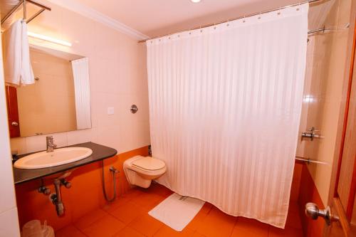 a bathroom with a shower and a toilet and a sink at Periyar Meadows Leisure Hotel in Thekkady