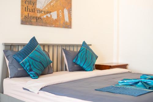 a bed with blue pillows on top of it at NO 7 Garden Villa in Rawai Beach