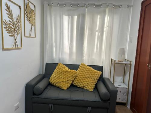a couch with two yellow pillows sitting in front of a window at Bayanihan Flats 2 in Pajak