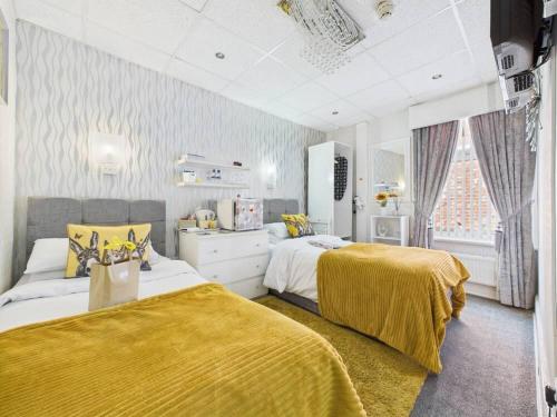a bedroom with two beds with yellow sheets and a window at Sorrento House in Blackpool
