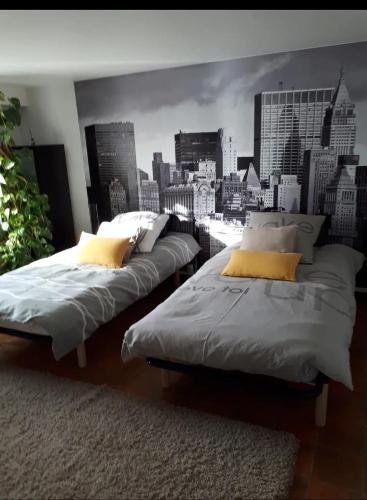 two beds in a room with a city mural at Porte de Paris in Saclay