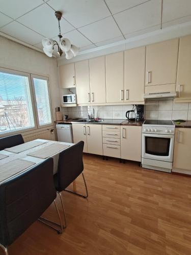 a kitchen with white cabinets and a table with chairs at Simple Cozy House in Raahe