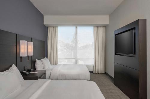 a hotel room with two beds and a flat screen tv at Residence Inn by Marriott Madison in Madison
