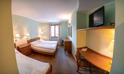 a small room with two beds and a television at Hotel Residence Valverde in Gressoney-la-Trinité