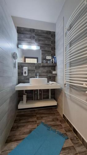 a bathroom with a white sink and a blue rug at Szofi Apartman in Hajdúszoboszló