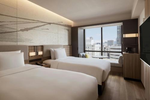 a hotel room with two beds and a large window at Courtyard by Marriott Osaka Honmachi in Osaka