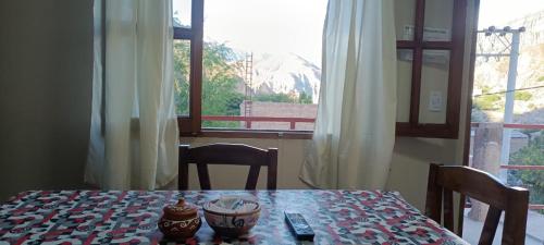 a table with two vases on top of it with a window at El Refugio Departamentos in Iruya