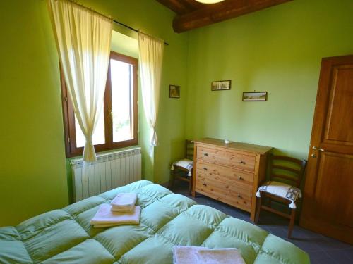 1 dormitorio verde con 1 cama y vestidor de madera en Scenic Apartment with Pool, en Poggio Alla Croce