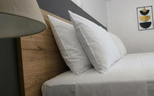 a pile of white pillows on a bed with a lamp at Mare Vento in Kiveri