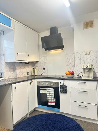 a kitchen with white cabinets and a blue rug at Aldershot Spacious 3-Bedroom House with Fast Wi-Fi & Free Parking in Aldershot