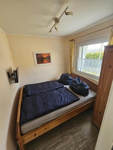 a bedroom with a bed with blue sheets and a window at Haus am Waldesrand in Wustrow
