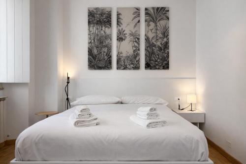 a bedroom with a white bed with three paintings on the wall at Bilocale in centro a 1 minuto da Piazza Unità in Trieste