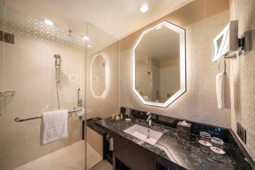a bathroom with a sink and a shower and a mirror at Marriott Hotel Jabal Omar Makkah in Mecca
