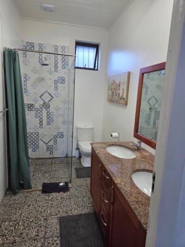 a bathroom with a shower and two sinks and a toilet at Ocean Rush in Zinkwazi Beach