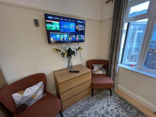 a room with two chairs and a tv on a wall at Cosy Budget Rooms in Camden Town near Regents Park in London