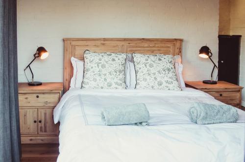 a bedroom with a white bed with pillows and two lamps at Genadendaal Vineyard Villa in Paarl