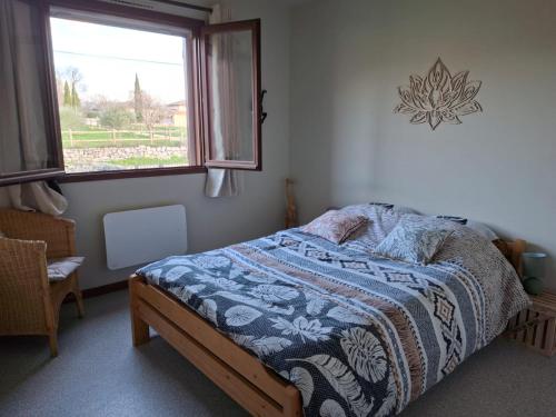 a bedroom with a bed with a blue and white blanket at Gîte Les hauts de Lenaly in Les Vans