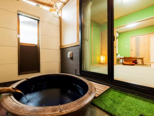 a bath tub in a room with a green rug at Koto no Kashin in Yufu
