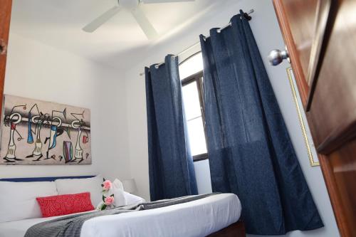 a bedroom with blue curtains and a couch and a window at Venus Bayahibe by Mireya in Bayahibe