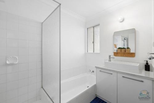 a white bathroom with a tub and a sink at Sea Gem in Lancelin