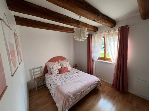 a bedroom with a bed with pink sheets and a window at Gîte de la Rouge Roye in Nompatelize