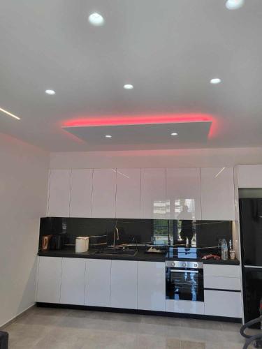 une cuisine avec des armoires blanches et une lumière rouge dans l'établissement Room cs, à Patras