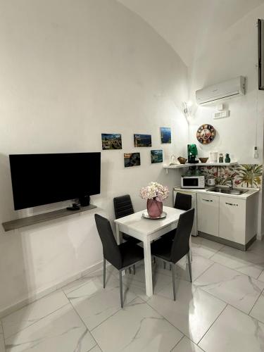 eine Küche mit einem Tisch mit Stühlen und einem Fernseher an der Wand in der Unterkunft Casa TeKa in Torre Annunziata