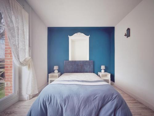 a blue bedroom with a bed and a window at Le Chalet du 1er étage, Appartement de charme de 80m2, 2 chambres in Bagnoles de l'Orne