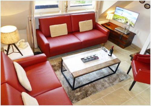 sala de estar con sofá rojo y mesa en FERIENWOHNUNG DEICHWIESE SYLT-WESTERLAND 2-5 Personen-3 Schlafzimmer-Terrasse, en Westerland