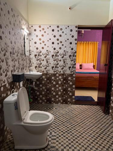 a bathroom with a toilet and a sink and a bedroom at Mud apples in Varkala