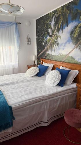 a bedroom with a large bed with blue and white pillows at Dahlias Bed & Breakfast in Väderstad